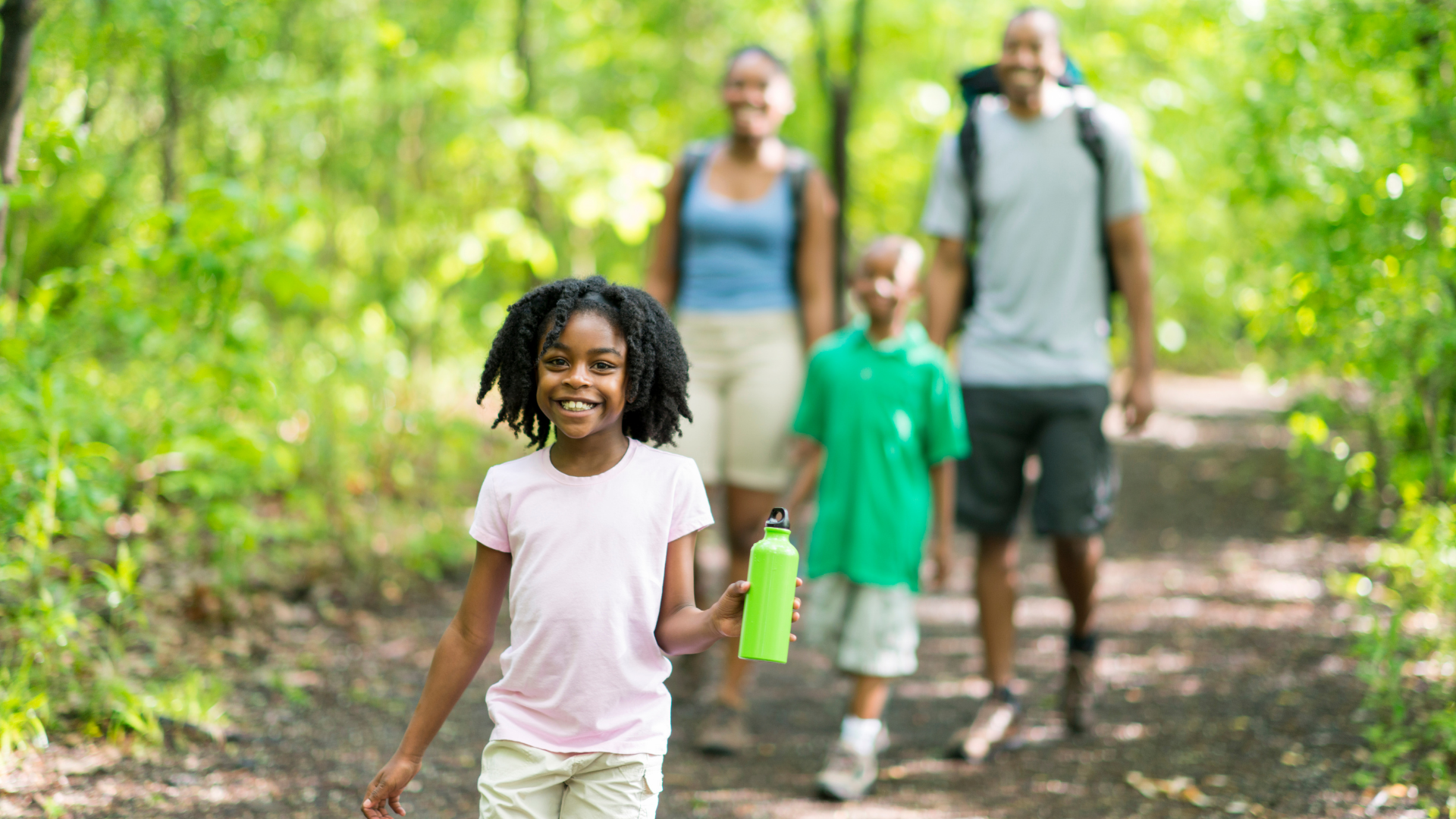 A family walks together on a wooded trail