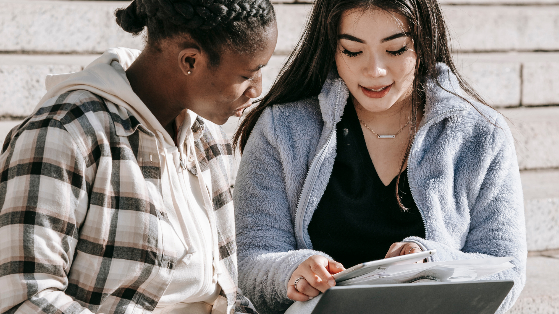 Two people collaborate over documents and a tablet