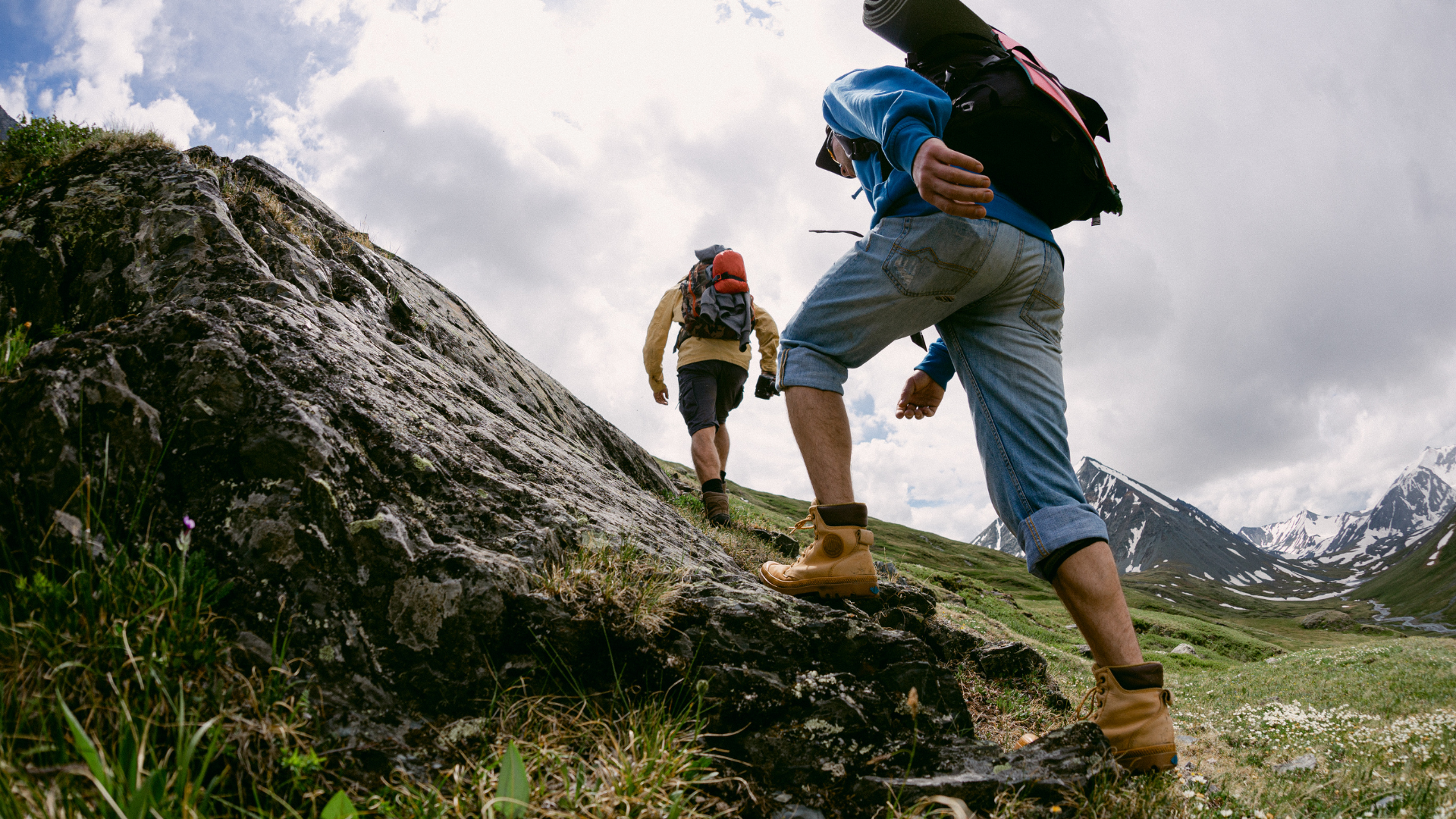 Two hikers climbing toward a mountain landscape